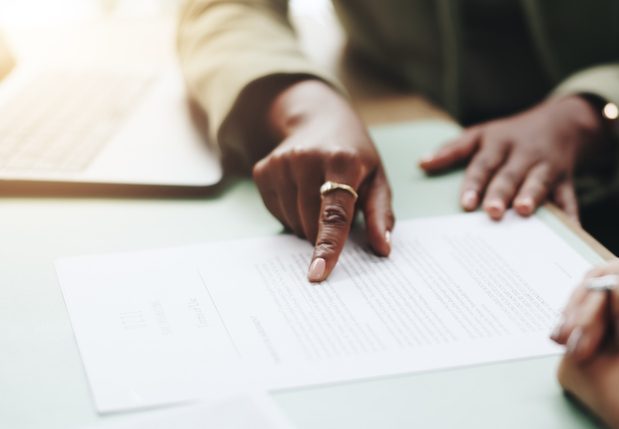 Business people, hands and pointing on contract for legal documents, application and agreement in office. Pen, closeup and person explain paperwork for policy, form or deal in workplace or company
